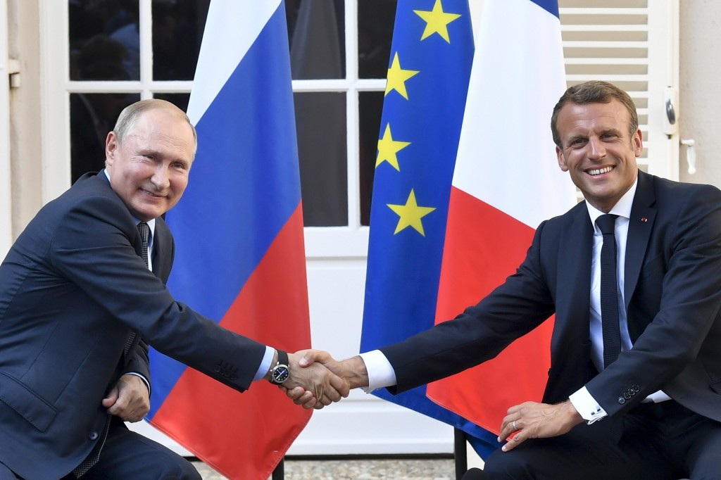 Emanuel Macron and Vladimir Putin shaking hands