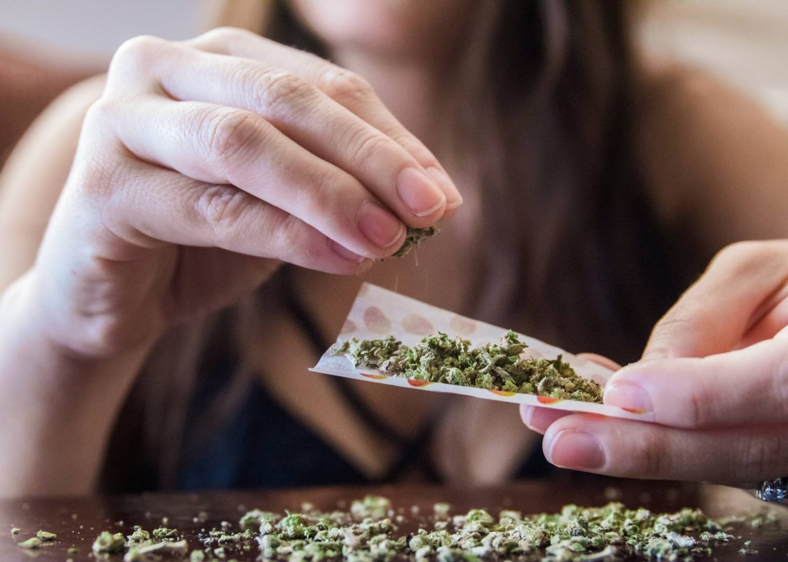 a woman rolling the paper to make weed cigarette