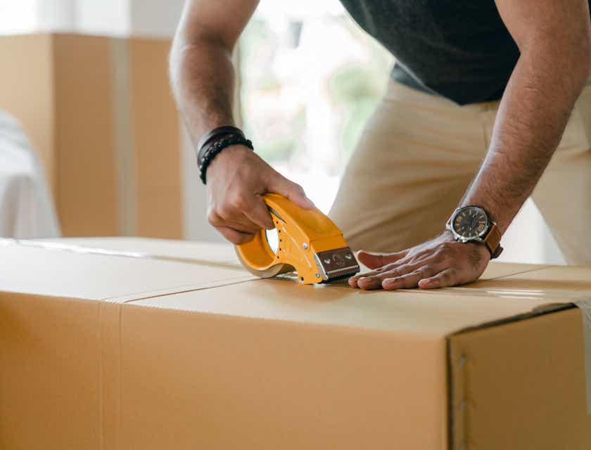 A worker sealing a box with tape